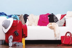 messy white couch covered in clothing getting orgnaised to pack