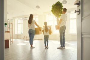 Family with moving boxes stepping into a new room